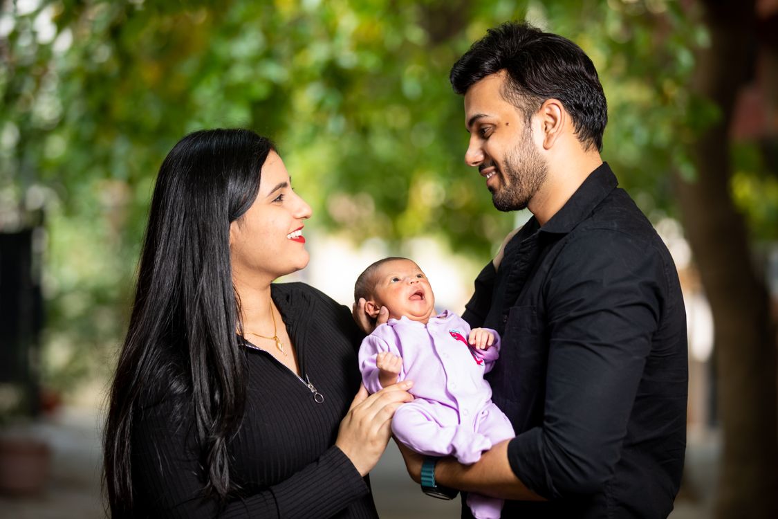 Indian parents holding their newborn baby outdoors